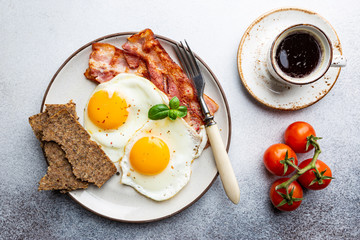 Fried eggs and bacon for breakfast on a plate, top view, copyspace