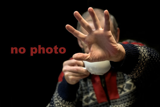 No pictures, please. Celebrity is hiding face with a hand from newspaper photographers