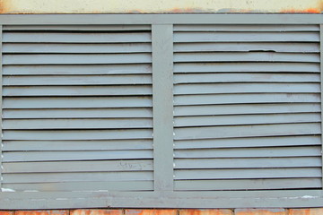 Fototapeta premium The iron grill on the wall in the form of blinds is painted gray.