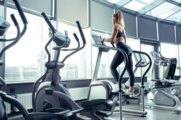 Young muscular caucasian woman practicing in gym, doing cardio. Athletic female model doing strength exercises, training her upper body. Wellness, healthy lifestyle, bodybuilding concept.