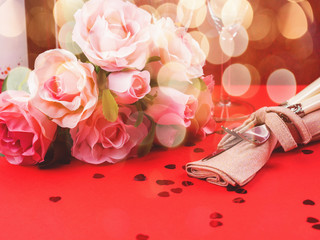 Festive woman, valentine day dinner concept on red background with heart confetti, rose flowers, envelope and elegant silverware on napkin.