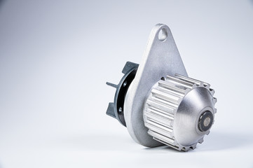 New metal automobile pump for cooling the engine of a water pump on a gray background. The concept of new spare parts for the car engine