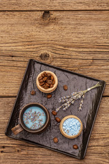 Fototapeta na wymiar Trendy colored latte. Lavender and powdered aromatic sugar, coffee beans. Wooden boards background