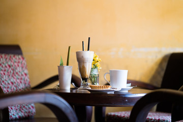 Coffee set on wooden table, yellow wall background.