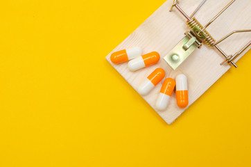 Mousetrap with pills on a yellow background. The concept of health, business