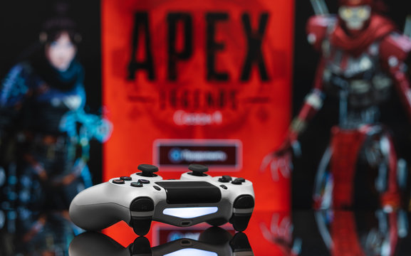 Odessa, Ukraine - February 9, 2020. White playstation 4 gamepad on the background of the game APEX Legends from EA Games. Apex Legends free to play Battle Royale shooting game.