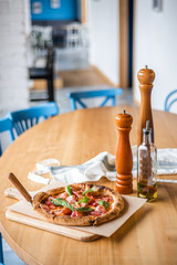 Delicious pizza stands on the table, pizza with red sauce, pancetta and basil, Italian cuisine, pizzeria