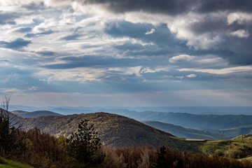 Fototapeta premium Dramatic autumn colorful view over the mountain range from near Shipka peak, Stara Planina mountain in Central Bulgaria as seen from Shipka Memorial. Moody feeling, sun rays, horizontal orientation
