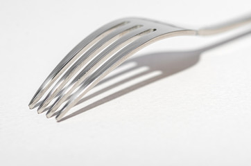 Two metal shiny forks on a light background.