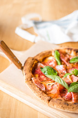 Delicious pizza stands on the table, pizza with red sauce, pancetta and basil, Italian cuisine, pizzeria