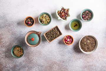 Assortment of dried tea in ceramic bowls. Black, green and herbal tea collections. Top view, copy space. Food background.