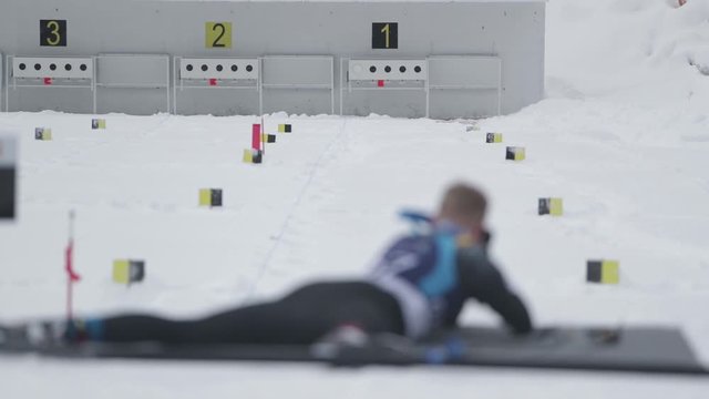 Slow motion footage of a person shooting from his rifle to the target at a biathlon contest, he misses one
