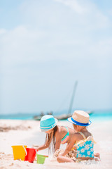 Two kids making sand castle and having fun at tropical beach