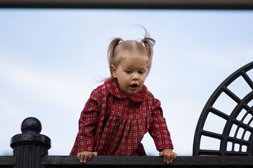 Portrait of curiosity caucasian child of two years old looking down from high point on the blue sky...