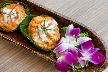 Steamed seafood with curry paste in banana leaf at restaurant.