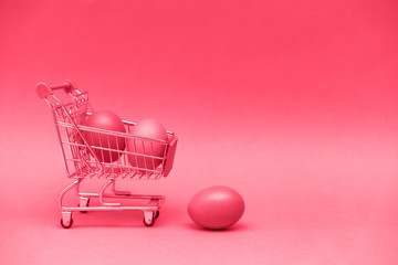 Shopping toy trolley with eggs on toning in red concept