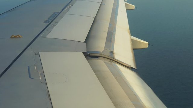 The point of view of the passenger plane. View through the window. The wing of an airplane that flies over the sea. The plane is preparing for landing.