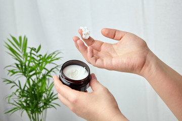 Shea butter in jar, cosmetic product for moisturizing skin. Female hand holds container with white anti-aging smoothing and soothing cream