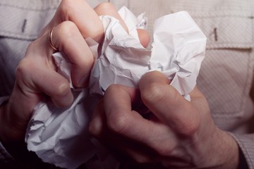 A man crushes business papers. Hands crumple the paper. The destruction of evidence. Contract cancellation. The concept of a disagreement, a conflict at work, a failed project, or a report.