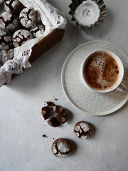 Chocolate crinkle cookies with powdered sugar icing in a box whith a cup of coffee
