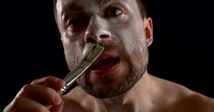 actor paints face using brush and preparing for performance