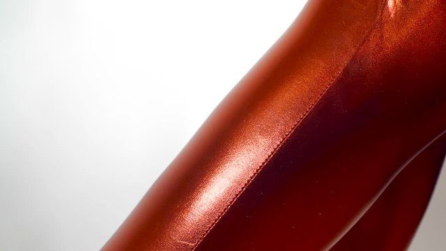 Extreme close up  shot of the hand  with manicure of girl in a tight  fitting shiny red zentai suit, plucking fabric on suit. Isolated on  white studio background. 4k 50 fps slow motion