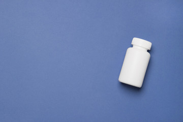 White plastic medical container for pills on right side of blue background with copy space