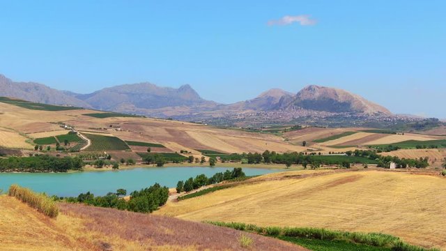 Aerial view of Patchwork crop fields, lake poma and mountains, italy