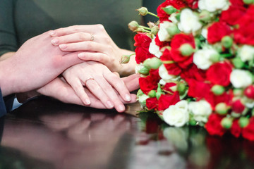 Obraz na płótnie Canvas Hands with an engagement ring against the background of a bouquet of roses