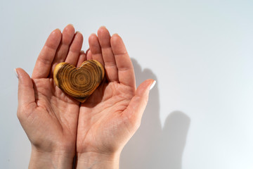 young woman holding a wooden heart in her hands, a gift for Valentine's day, white background, copy space to the right, horizontal frame