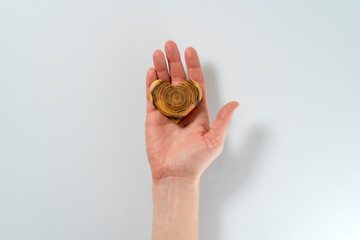 only the hand of a young woman holding a wooden heart, a gift for Valentine's day, centered white background, copy space, horizontal frame