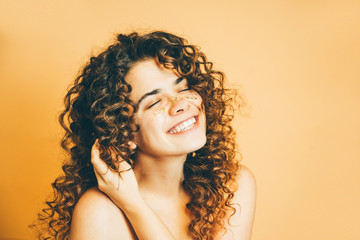 Portrait of beautiful girl with curly hair smiling with close eyes.