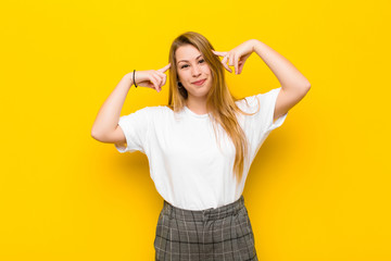 young blonde woman feeling confused or doubting, concentrating on an idea, thinking hard, looking...