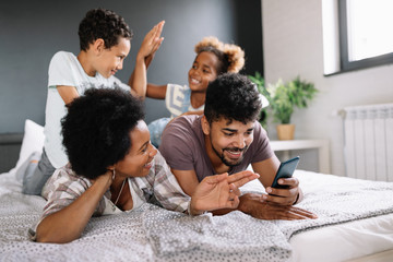 Parents with children enjoying playing games or entertaining using mobile apps on phone at home