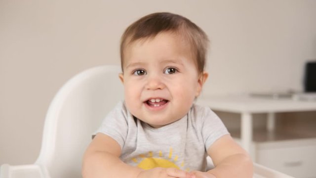 Baby with flu laughing at high chair feels happy at home. Portrait of smiling baby boy