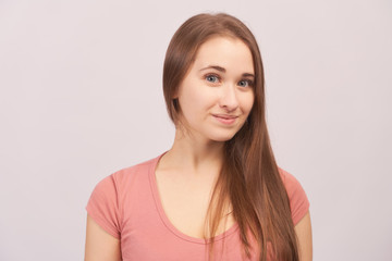 Fototapeta premium Portrait of smiling girl grins at camera, grinning, eyes glistening. Beautiful young woman with long hair isolated on white background in Studio with an empty space for text and advertising.