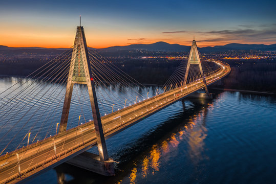 Budapest, Hungary - Aerial view of the beautiful illuminated cable-stayed Megyeri Bridge over River Danube with blue and orange sky at sunset