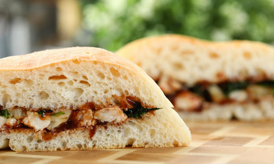 Cut chiken sandwich with ketchup against kitchen closeup background.