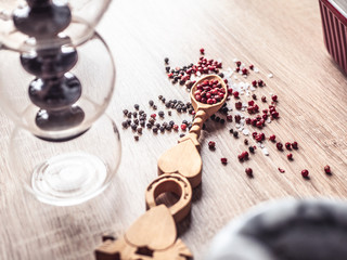 Black and red pepper on a vintage spoon. Variety of spices on wooden kitchen table.