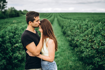 Young loving couple gently hugging on the background of green currant plantations. Love Story