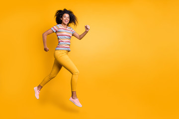 Fototapeta na wymiar Full length body size view of nice attractive sportive cheerful cheery wavy-haired girl in striped t-shirt jumping running fast flying isolated on bright vivid shine vibrant yellow color background