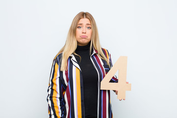 young pretty blonde woman sad, depressed, unhappy, holding a number 4.