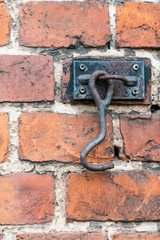 A metal hook mounted on a red brick wall