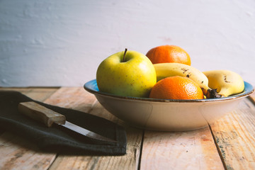 Some natural fruit on a wooden table in a rustic kitchen next to a knife. Empty copy space and white background for Editor's content.