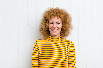 young pretty woman looking happy and friendly, smiling and winking an eye at you with a positive...