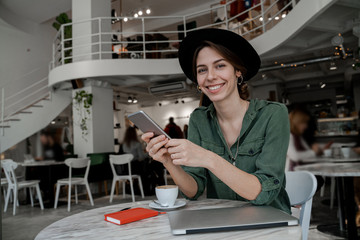 Happy stylish smiling woman looking at camera, having break for coffee in cafe. Freelancer, entrepreneur, work in cowering space, public place, modern people lifestyle, business online concept.