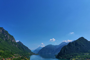 Obraz premium Panoramic view of the mountains and Lake Idro. Reflection in the water of the mountains, trees, blue sky. Aerial view, drone photo