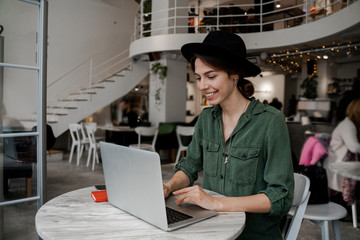 Woman traveller hipster work remotely in cafe in her travel time. Freelancer, entrepreneur, work in cowering space, public place, modern people lifestyle, business online concept.