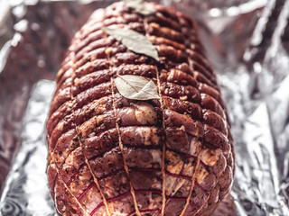 Baking tray with smoked meatloaf on table. Cooked spicy pork meat roulade prepared to roast, marinated with spices and herbs on black slate plate.