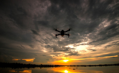 drone quadcopter with digital camera flying at sunset.Dark Flying drone and cloud sunrise sky.